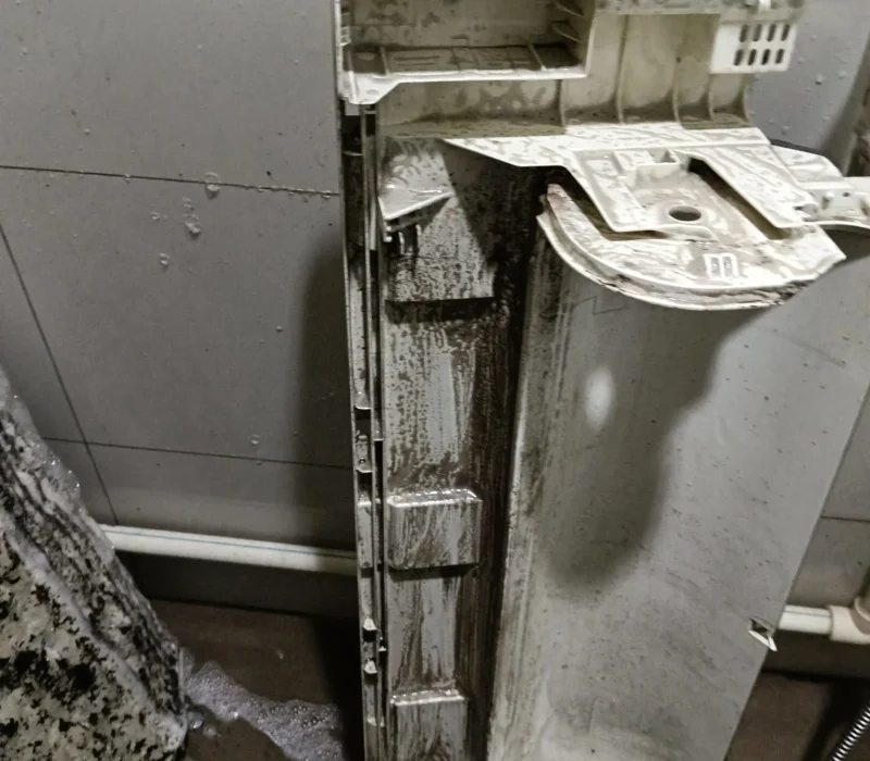 Plastic air conditioner back casing covered in soapy foam and dirt residue during a chemical overhaul.