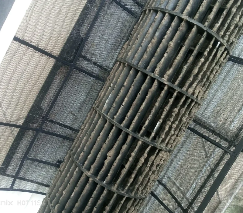 Close-up of a heavily soiled air conditioner blower wheel covered in thick dust and mold buildup.